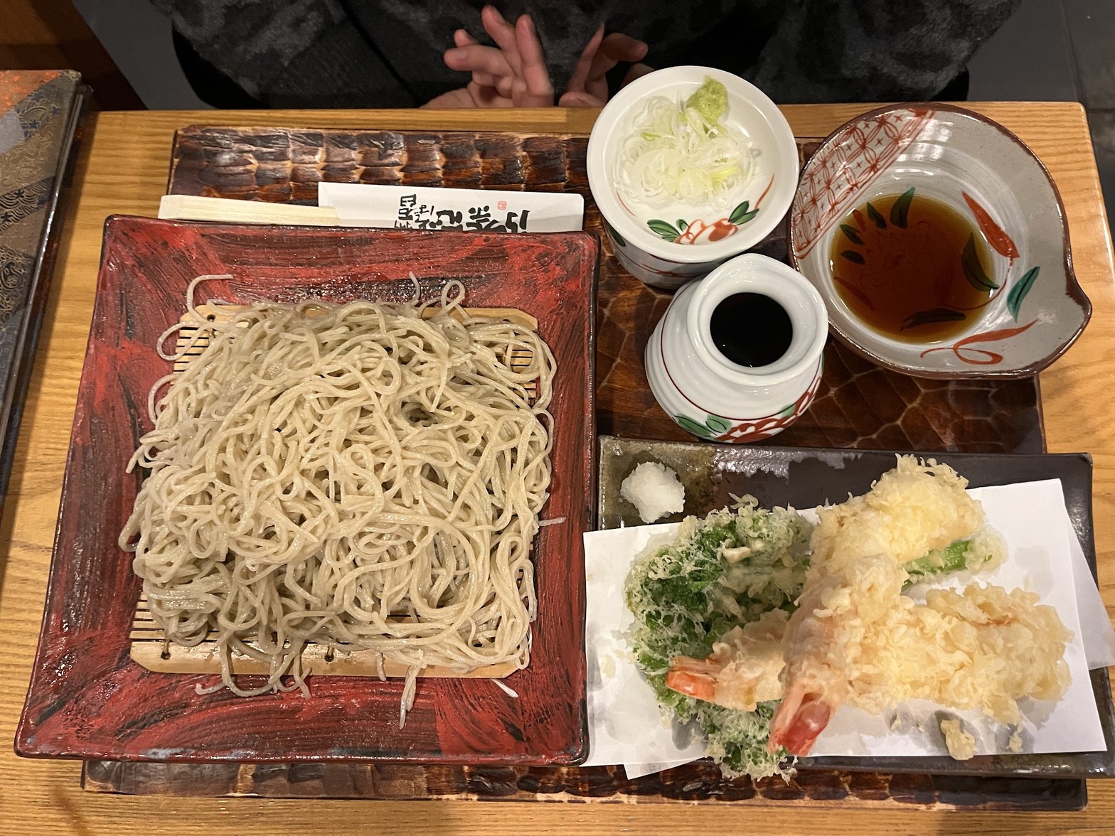 赤い角皿の蕎麦と天ぷら数種、薬味小皿2つ・蕎麦つゆ・天つゆが横並びに並ぶ天ざるセット